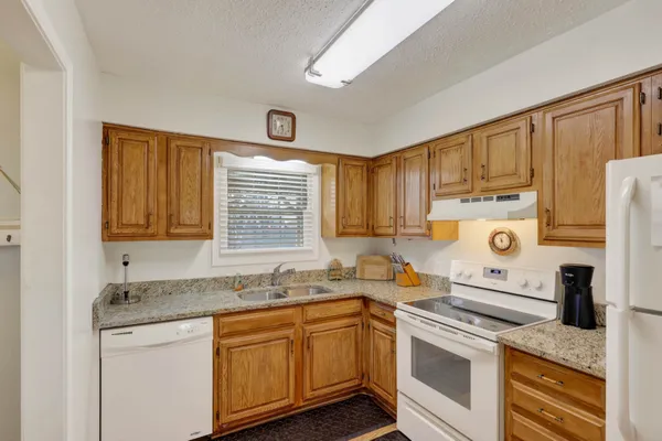 a kitchen with granite countertop a sink stove and cabinets