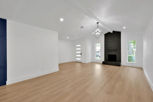 an empty room with wooden floor fireplace and windows