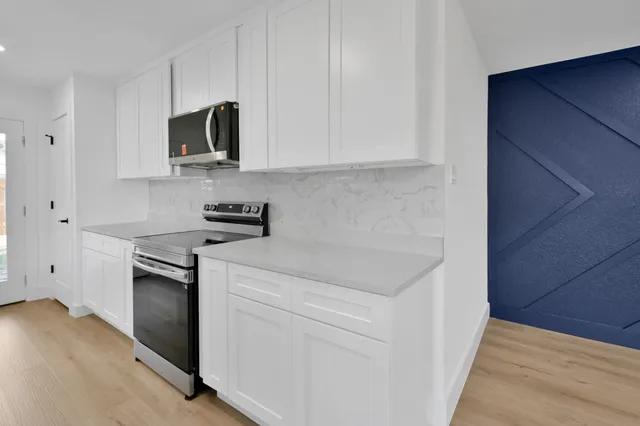 a kitchen with white cabinets and stainless steel appliances
