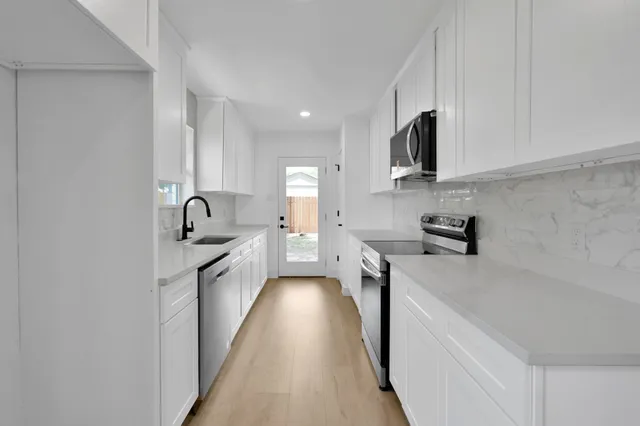 a kitchen with stainless steel appliances a sink stove top oven and cabinets