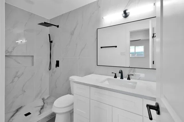 a bathroom with a sink toilet a mirror and shower