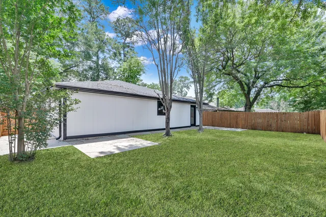 a backyard of a house with lots of plants and large tree