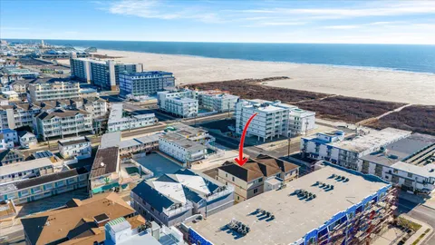 a front view of a building with glass windows and plants