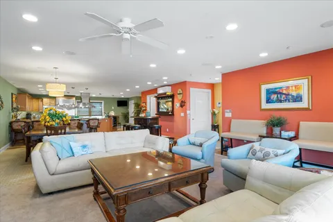 a living room with furniture kitchen view and a chandelier