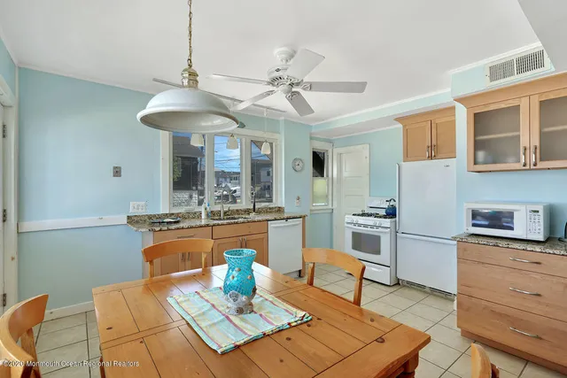 a kitchen with a stove a sink dishwasher a dining table and chairs with wooden floor
