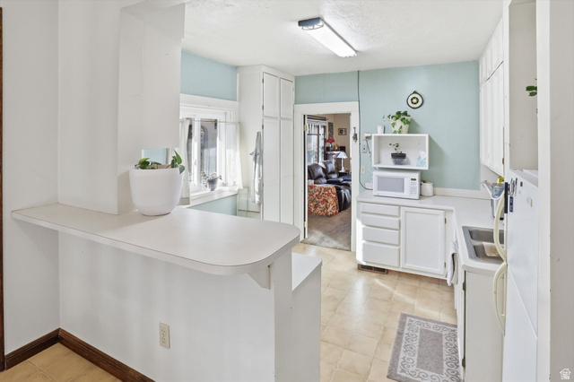 380 North 200 West Logan, UT 84321 - Photo 8 of 29 Kitchen featuring white cabinets, light countertops, white appliances, and a peninsula