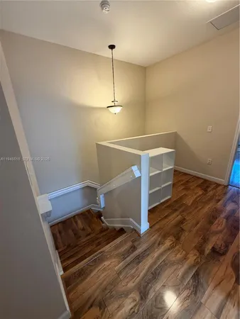 an empty room with wooden floor fan and window