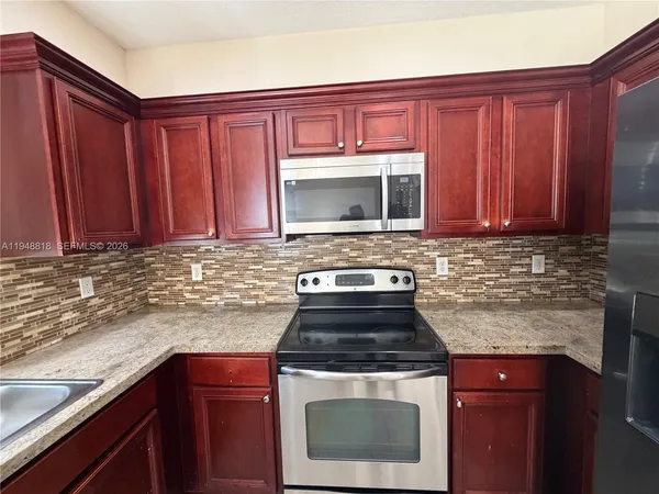 a kitchen with stainless steel appliances granite countertop a refrigerator and a stove
