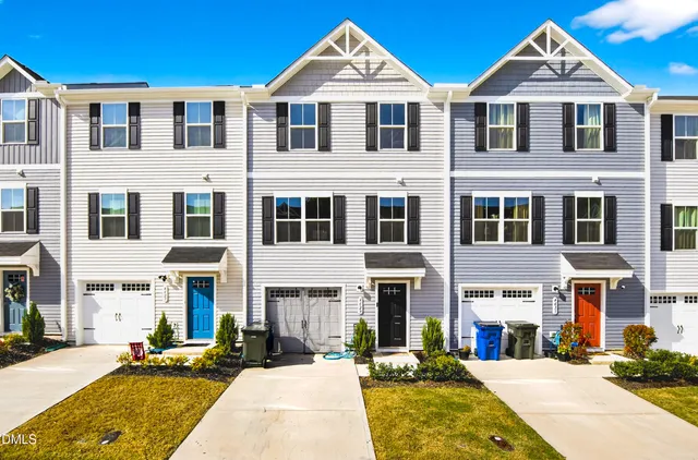 a view of a white building with many windows next to a yard