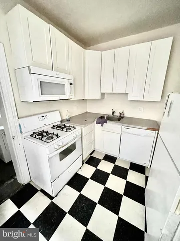 a kitchen with a checkered floor and white cabinets