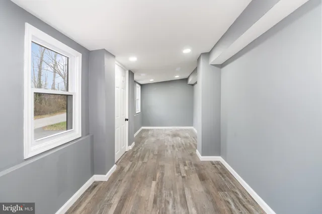 a view of hallway with window and wooden floor