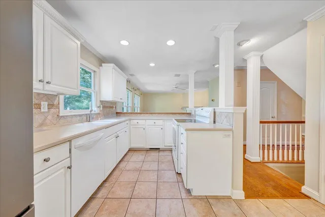 a kitchen with a sink a stove top oven cabinets and a window