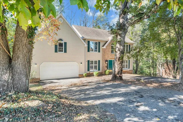 a view of a white house next to a road and yard