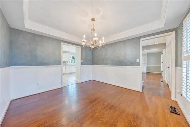 a view of a hallway with wooden floor and a chandelier
