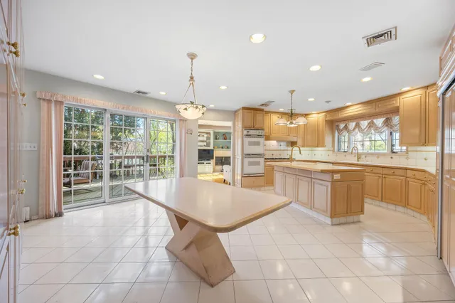 a large kitchen with kitchen island a sink a stove a refrigerator and white cabinets with wooden floor