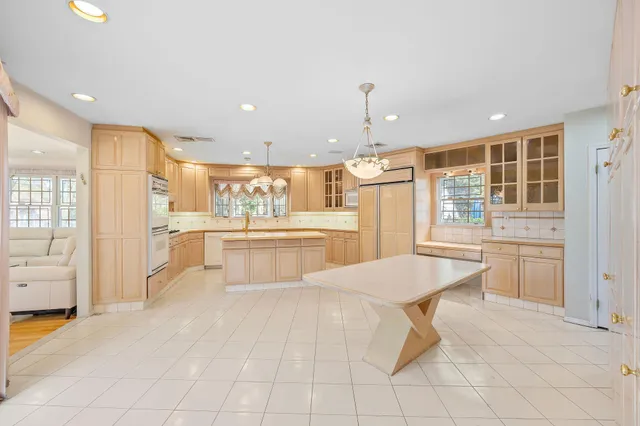 a large white kitchen with kitchen island a sink a stove a refrigerator and cabinets
