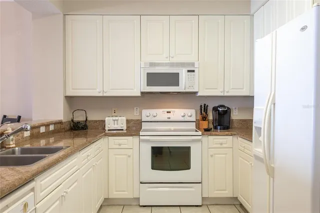 a kitchen with granite countertop white cabinets and white appliances