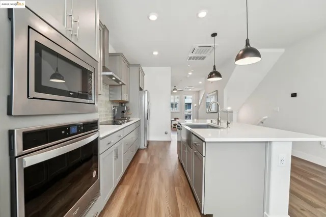 a kitchen with stainless steel appliances white cabinets and wooden floors