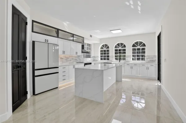 a large white kitchen with granite countertop a stove and a sink