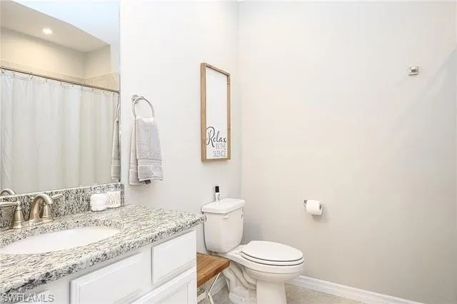 a bathroom with a granite countertop sink a toilet and a mirror