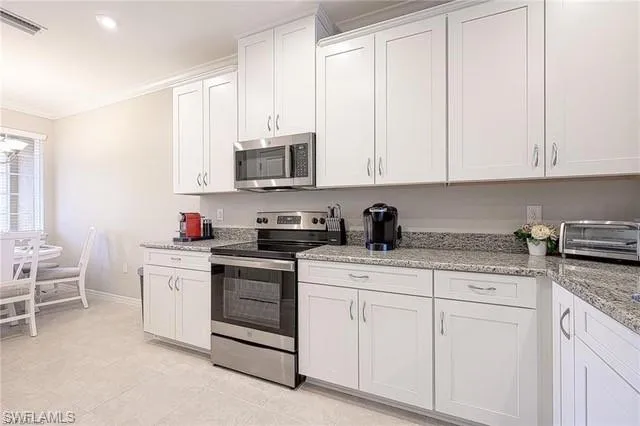 a kitchen with granite countertop white cabinets sink and stainless steel appliances