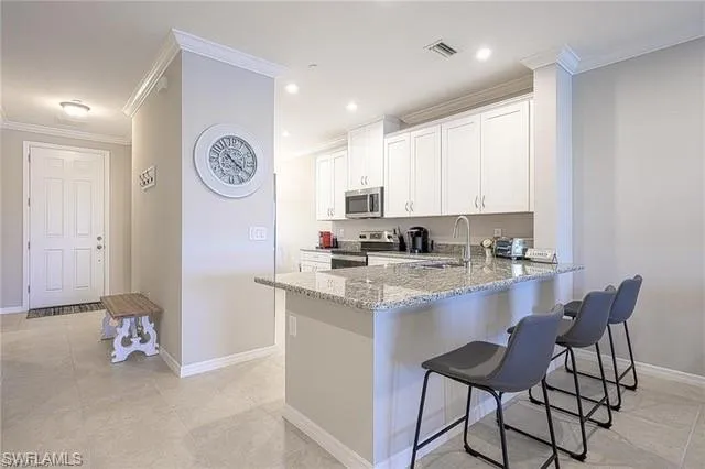 a kitchen with stainless steel appliances granite countertop a stove top oven a sink a refrigerator and white cabinets