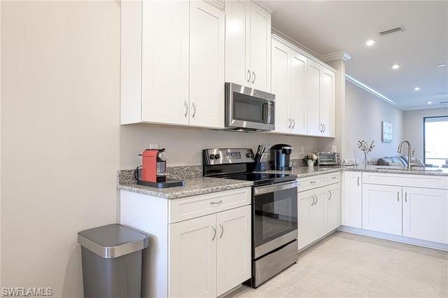 9365 Pocida Court, Unit 102 Naples, FL 34119 - Photo 7 of 38 a kitchen with stainless steel appliances granite countertop white cabinets a sink and a stove