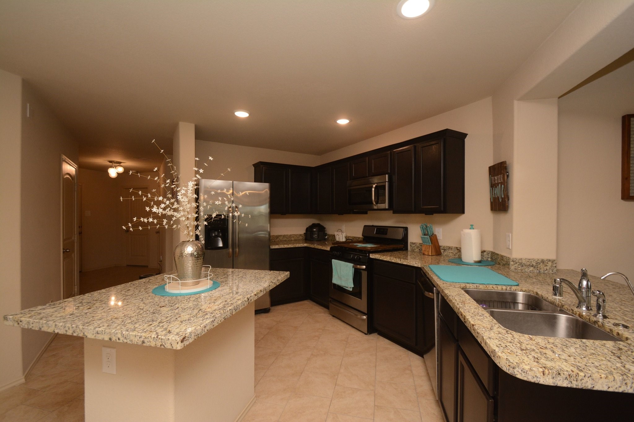 23318 Dukes Run Drive Spring, TX 77373 - Photo 9 of 41 This kitchen features dark wood cabinets, granite countertops, and stainless steel appliances, offering a modern and inviting space. The open layout includes a central island with stylish decor, ideal for cooking and entertaining.