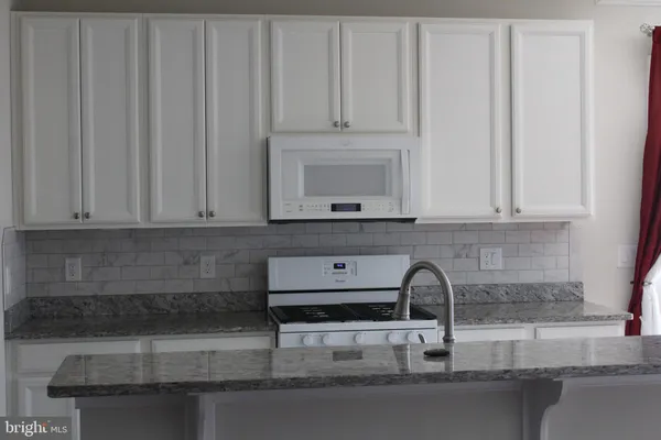 a kitchen with granite countertop white cabinets and sink