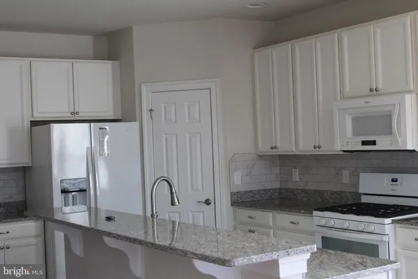 a kitchen with granite countertop white cabinets and stainless steel appliances