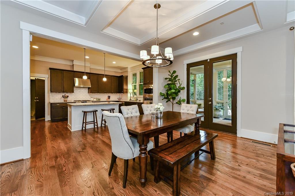 4935 Sharon View Road Charlotte, NC 28226 - Photo 15 of 48 a dining room with wooden floor a chandelier a wooden table and chairs
