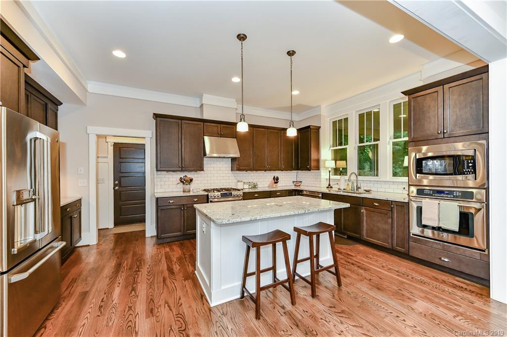 4935 Sharon View Road Charlotte, NC 28226 - Photo 16 of 48 a kitchen with stainless steel appliances granite countertop a stove top oven a refrigerator a sink dishwasher and a dining table with wooden floor
