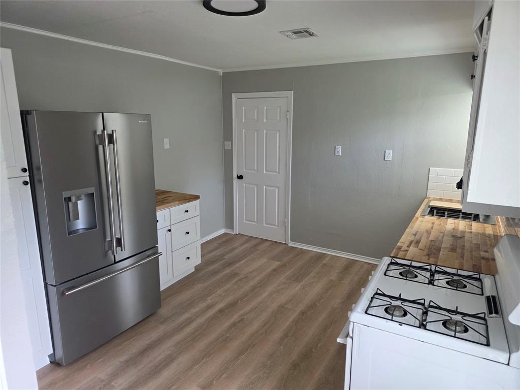 2804 Summer Avenue Waco, TX 76708 - Photo 9 of 13 Kitchen featuring wood-finish flooring, light grey walls, and white cabinetry