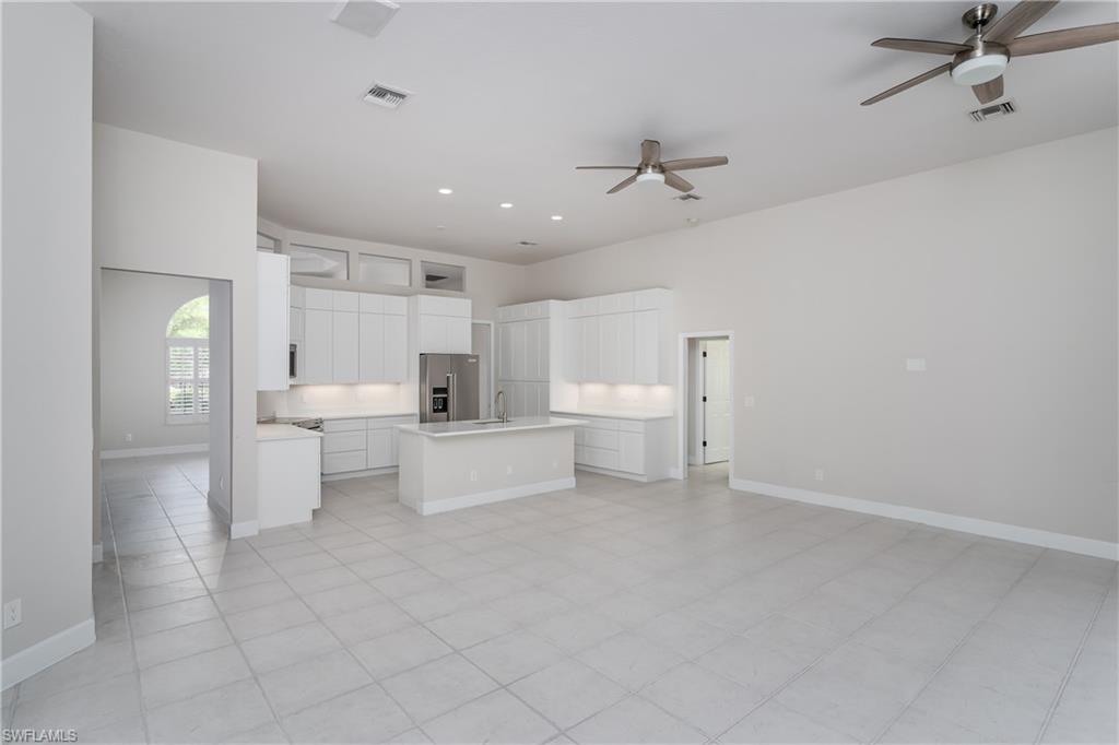 2280 Hawks Ridge Loop Naples, FL 34105 - Photo 11 of 33 Kitchen with high end fridge, sink, white cabinetry, a kitchen island, and ceiling fan