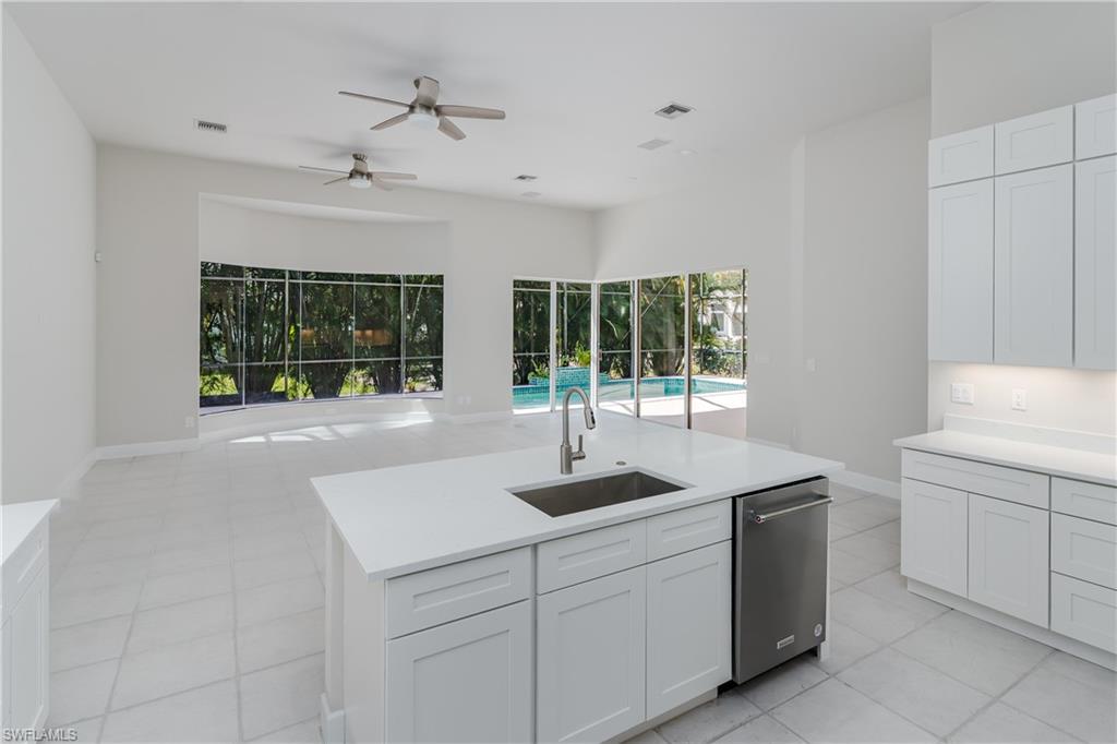 2280 Hawks Ridge Loop Naples, FL 34105 - Photo 12 of 33 Kitchen featuring dishwasher, sink, white cabinets, light tile patterned floors, and a center island with sink