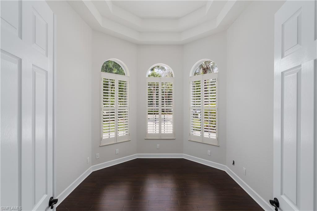 2280 Hawks Ridge Loop Naples, FL 34105 - Photo 15 of 33 Empty room featuring dark wood-type flooring and a tray ceiling