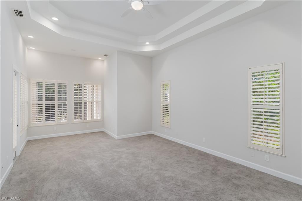 2280 Hawks Ridge Loop Naples, FL 34105 - Photo 16 of 33 Unfurnished room featuring a towering ceiling, light colored carpet, a raised ceiling, and ceiling fan