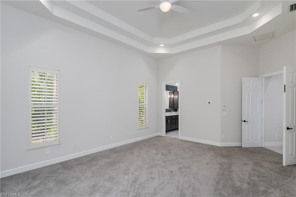 2280 Hawks Ridge Loop Naples, FL 34105 - Photo 18 of 33 Carpeted empty room with a high ceiling, a raised ceiling, and ceiling fan
