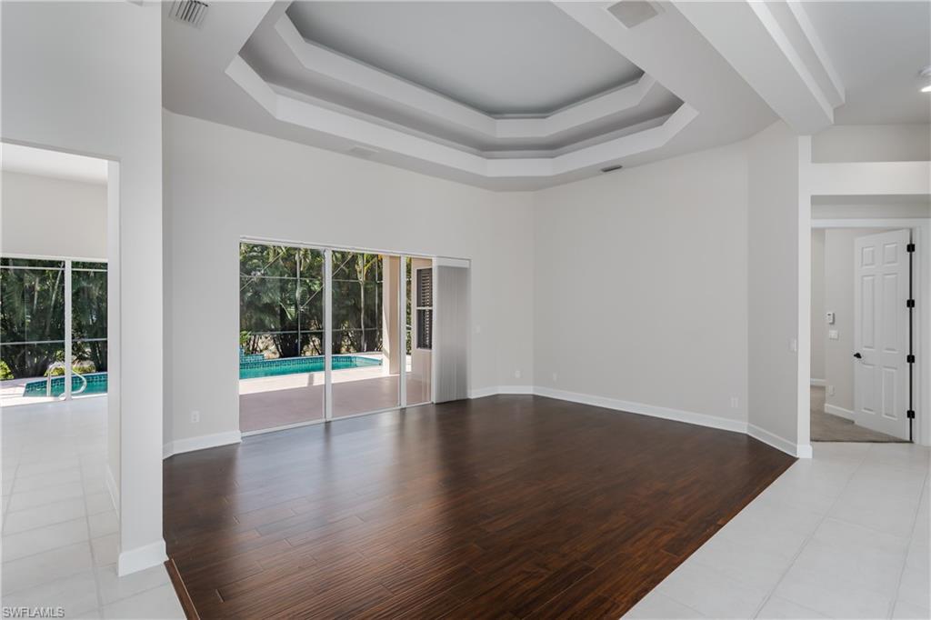 2280 Hawks Ridge Loop Naples, FL 34105 - Photo 2 of 33 Living room with a raised ceiling, a towering ceiling, and light hardwood / wood-style flooring