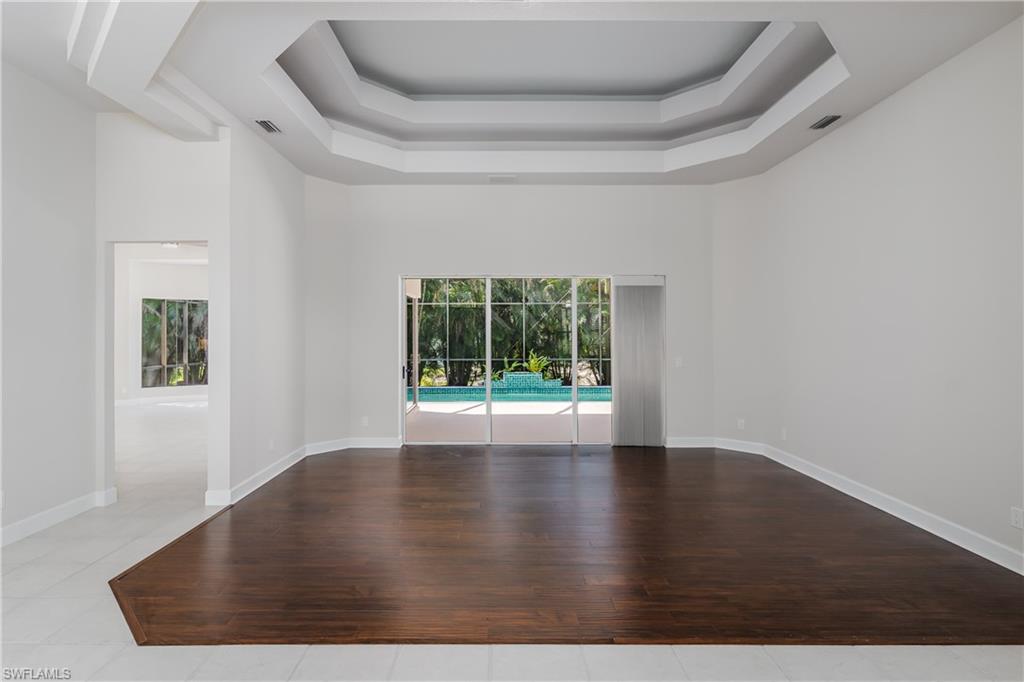 2280 Hawks Ridge Loop Naples, FL 34105 - Photo 3 of 33 Empty room with a raised ceiling, a towering ceiling, and light hardwood / wood-style floors