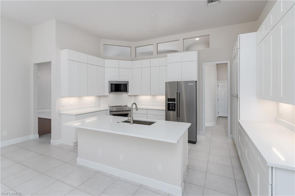 2280 Hawks Ridge Loop Naples, FL 34105 - Photo 8 of 33 Kitchen with white cabinetry, stainless steel appliances, sink, and an island with sink
