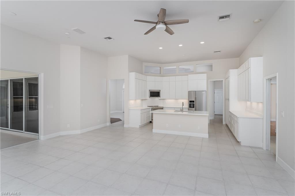 2280 Hawks Ridge Loop Naples, FL 34105 - Photo 10 of 33 Kitchen featuring built in microwave, white cabinetry, sink, high end refrigerator, and a center island with sink