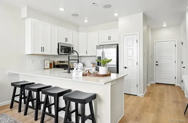 a living room with stainless steel appliances kitchen island granite countertop furniture a rug kitchen view and a chandelier