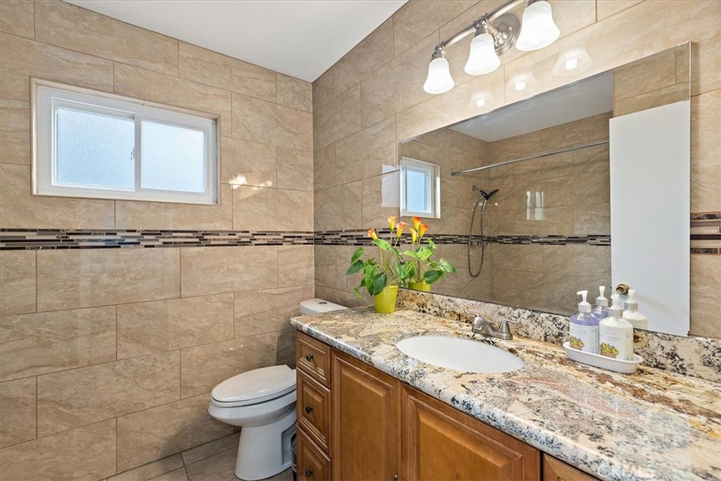 2914 West Wilson Street Banning, CA 92220 - Photo 13 of 31 a bathroom with a granite countertop sink a toilet and a mirror