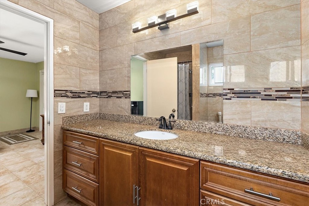 2914 West Wilson Street Banning, CA 92220 - Photo 21 of 31 a bathroom with a granite countertop sink a mirror and a shower
