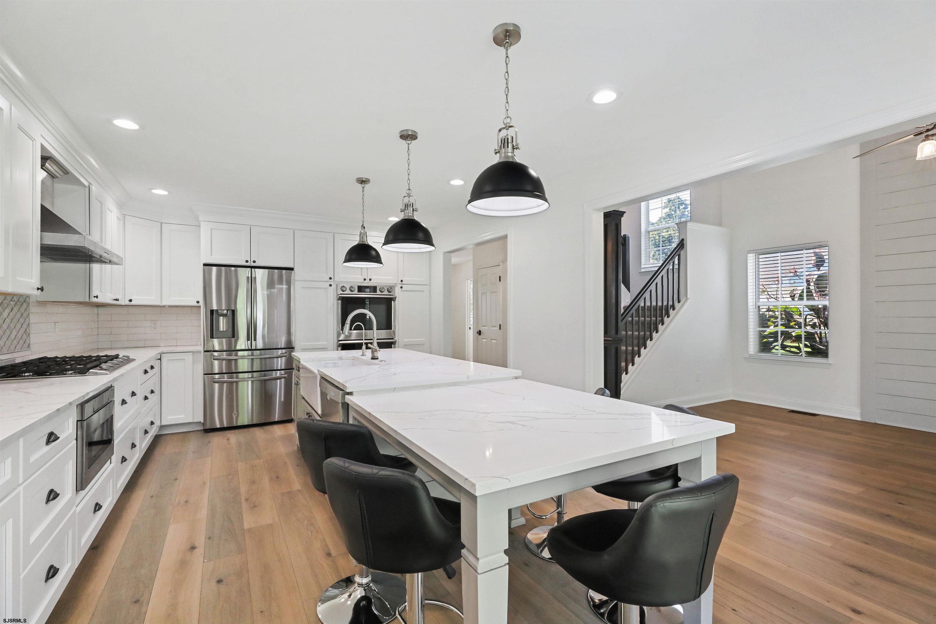 34 Kay Drive Hammonton, NJ 08037 - Photo 8 of 23 a kitchen with stainless steel appliances a stove a sink a refrigerator and chairs with wooden floor