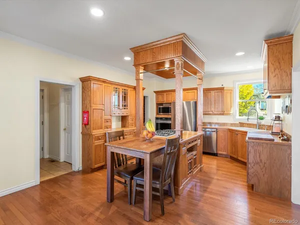a dining hall with stainless steel appliances kitchen island granite countertop a dining table and chairs with wooden floor