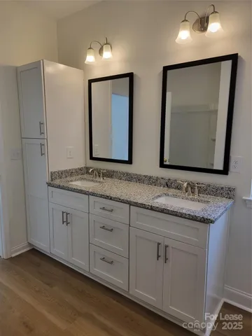 a bathroom with a granite countertop double vanity sink and mirror