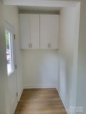 a view of an empty room with wooden floor and cabinet
