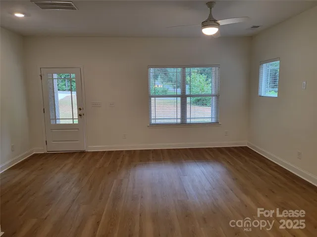 a view of an empty room with wooden floor and a window